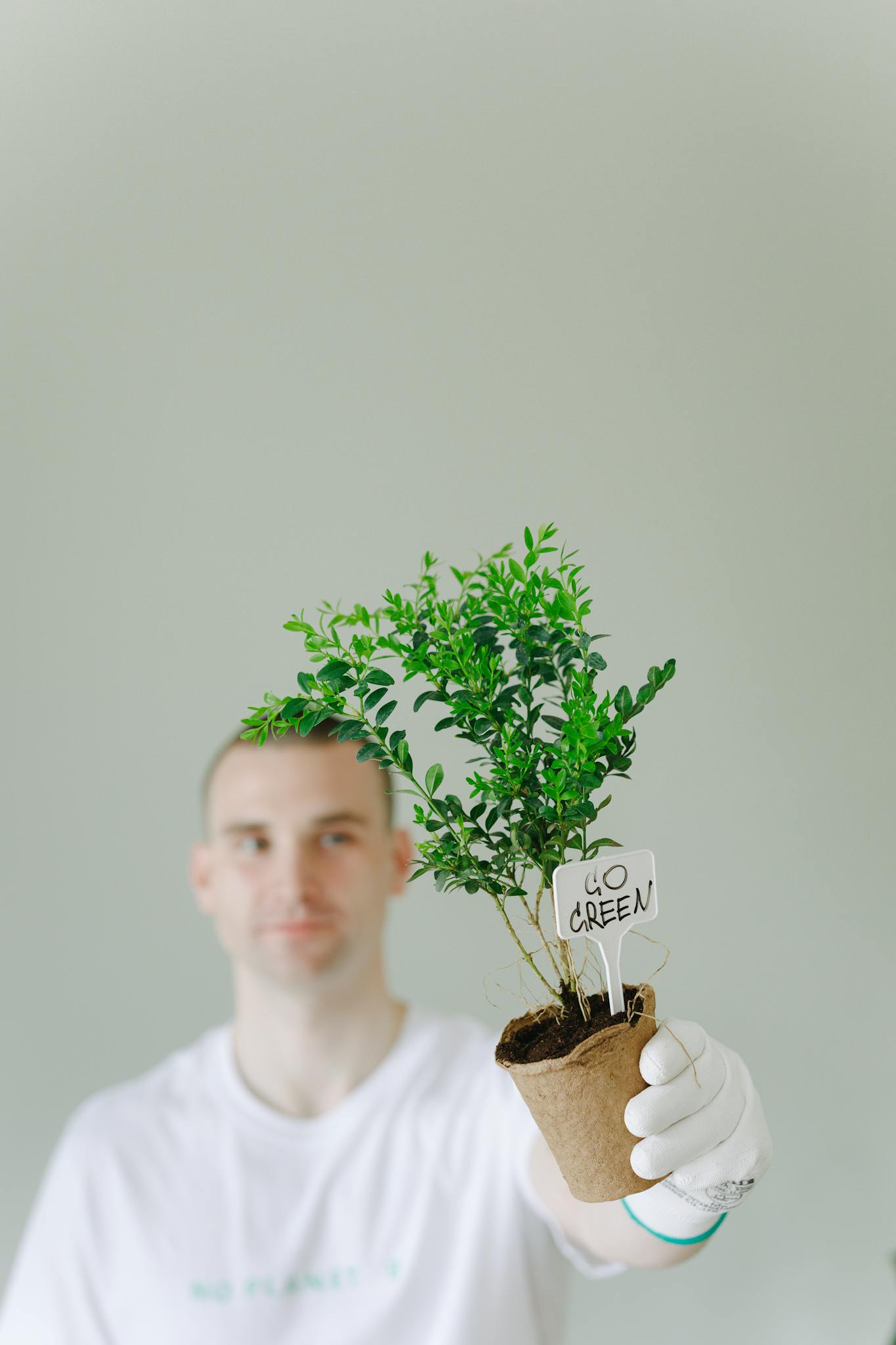 A man holding a potted plant, advocating for a greener lifestyle.
