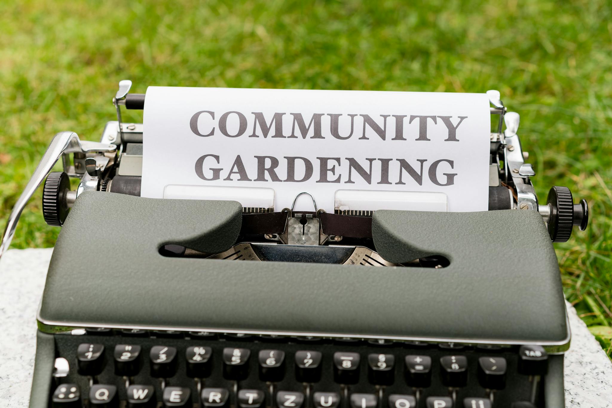 Vintage typewriter displaying community gardening message on paper outdoors.